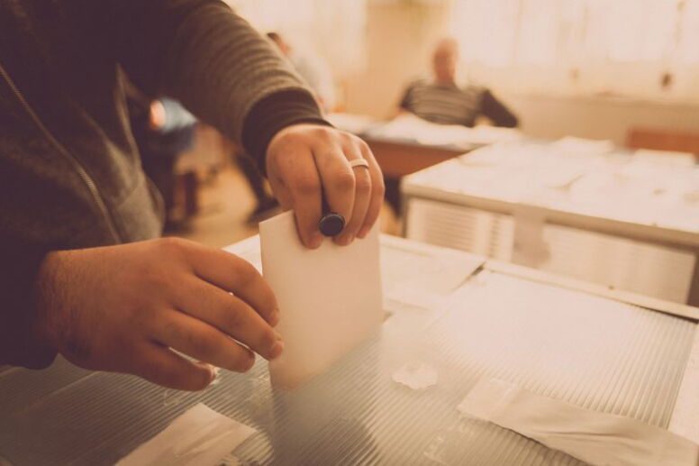 Man hands putting ballot in box